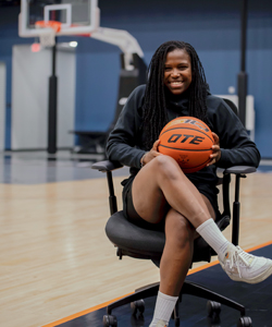 Sheila Dixon on a basketball court sitting while holding a basketball