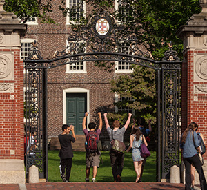 Four students walking through the Van Wickle Gates toward University Hall