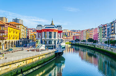 colorful buildings lining a waterway in Bilbao, Spain