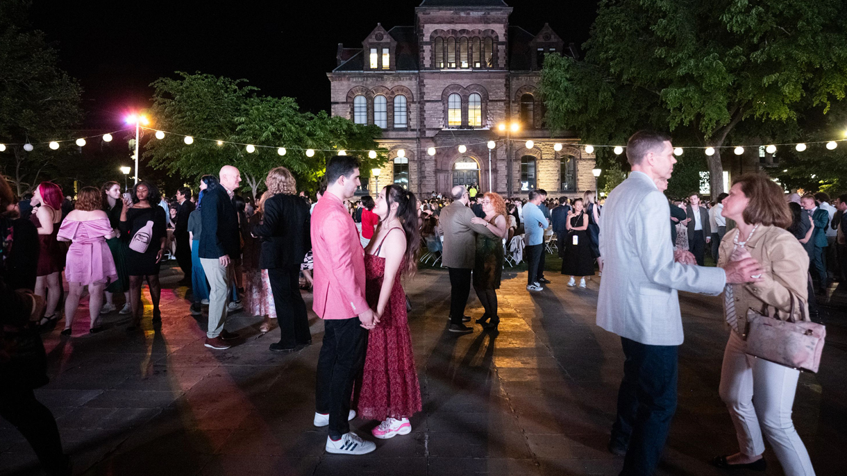 Alumni and graduating Brown students on the dance floor at Campus Dance with Sayles Hall in the background.