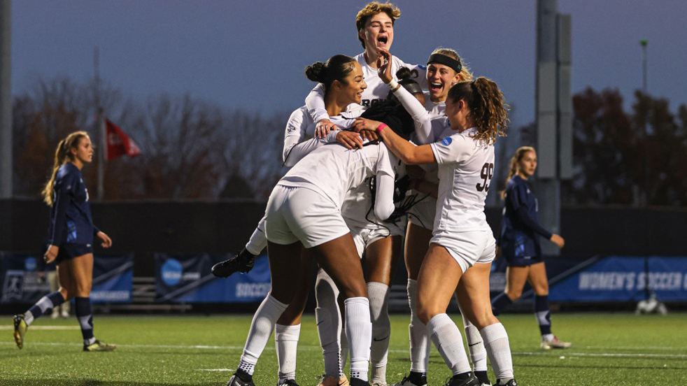 Members of the Brown women's soccer team on the pitch celebrating.