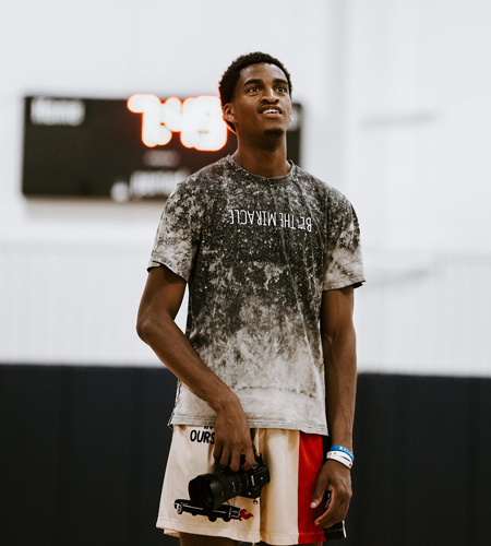 Aaron Cooley posing with a camera on a basketball court