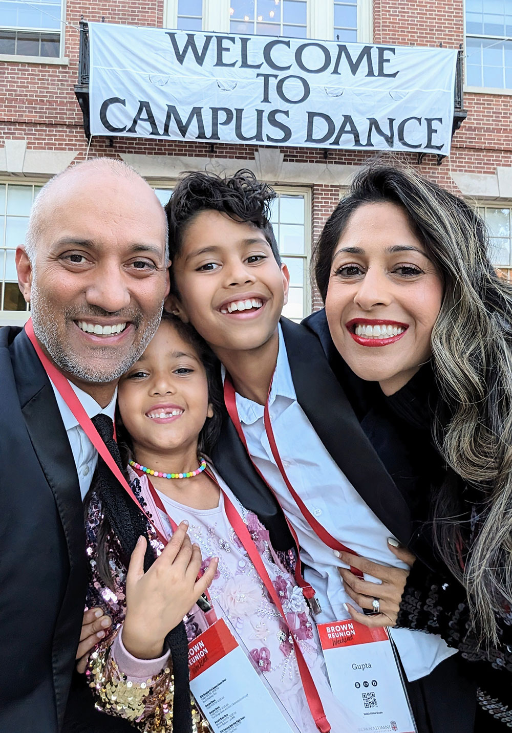 Abhas, Shaily, and their two children pose in front of a Campus Dance banner at Brown. 