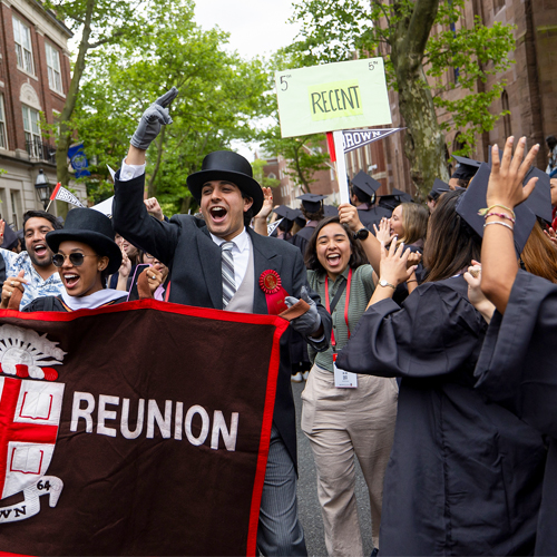 Alums celebrating their 5th Reunion walk in Procession while holding their class banner and cheering.