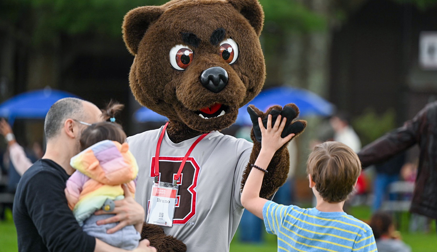 Bruno high fiving a child at a Brown Reunion event.