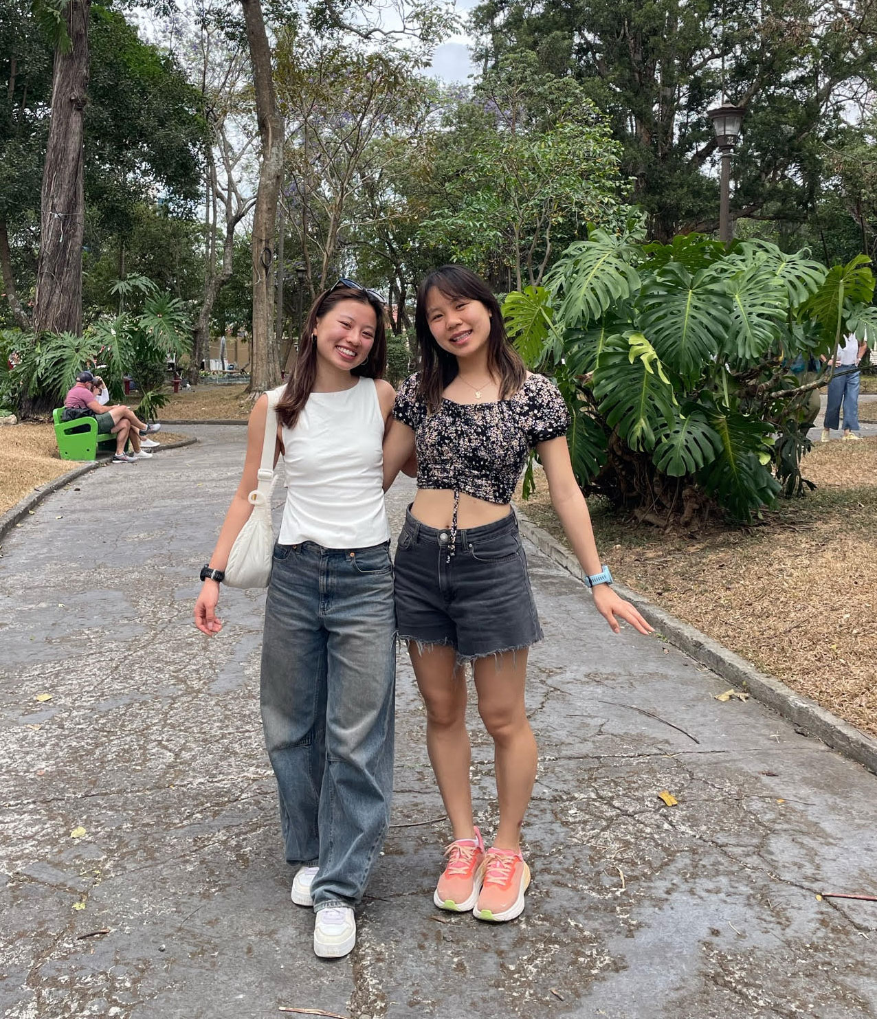 Denika and Lauren standing together outdoors surrounded by trees and plants.