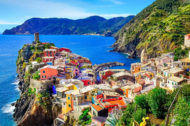 Colorful houses nestled atop a jutting peninsula over the Italian coast.