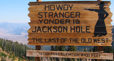 A crude wooden sign that reads Howdy Stranger Yonder is Jack Hole The Last of the Old West with a black silhouette of a woman pointing toward the left.