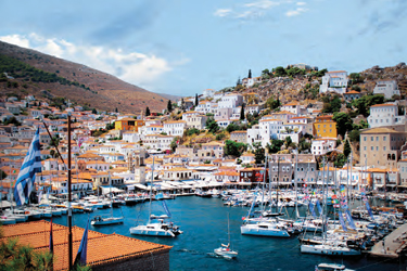A coastal Greek city with boats in the harbor.