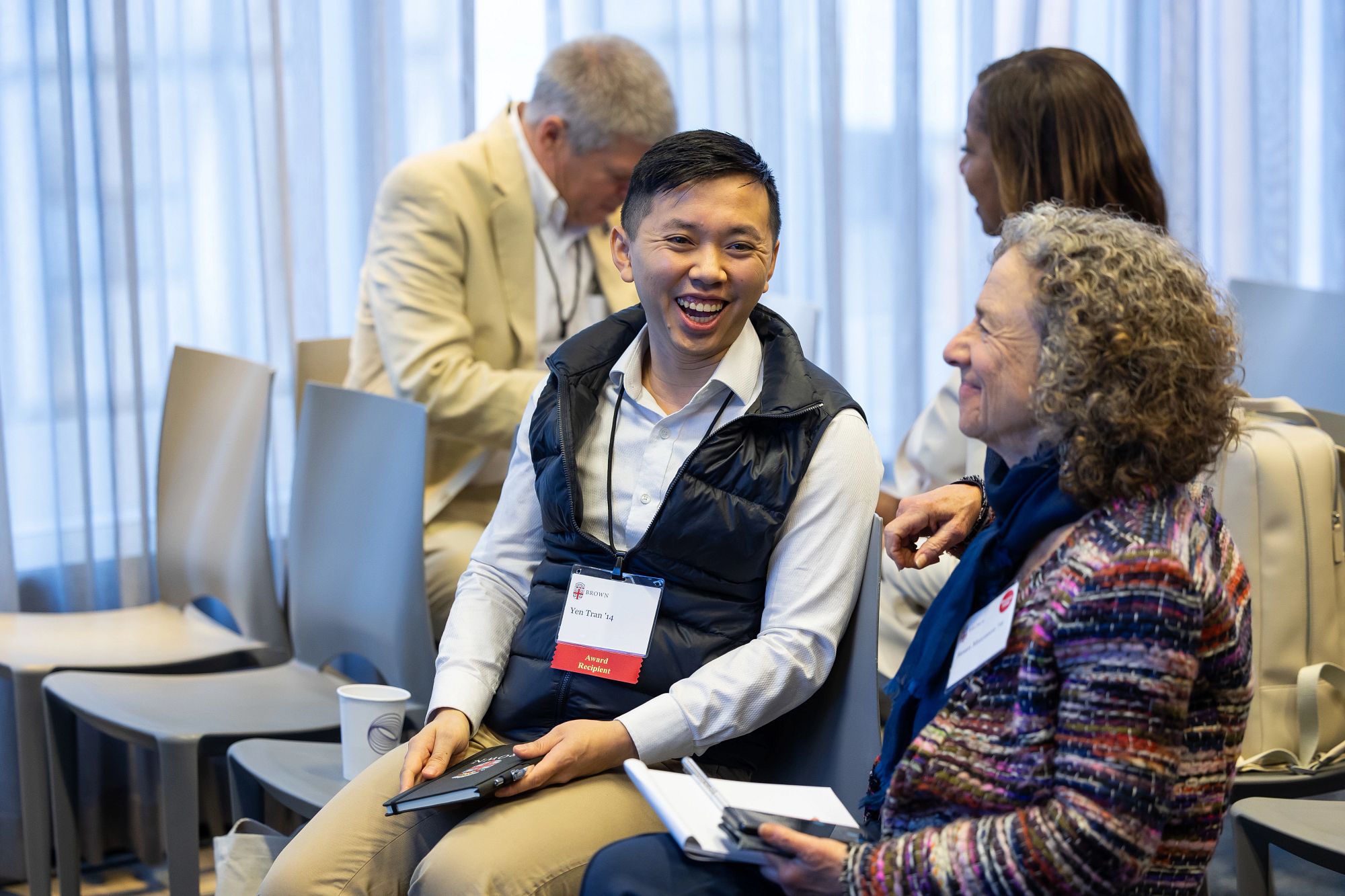 Yen at Brown’s Volunteer Summit, sitting next to another person, laughing. 