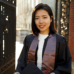 Joy Zheng standing outside the Van Wickle Gates during Commencement at Brown.