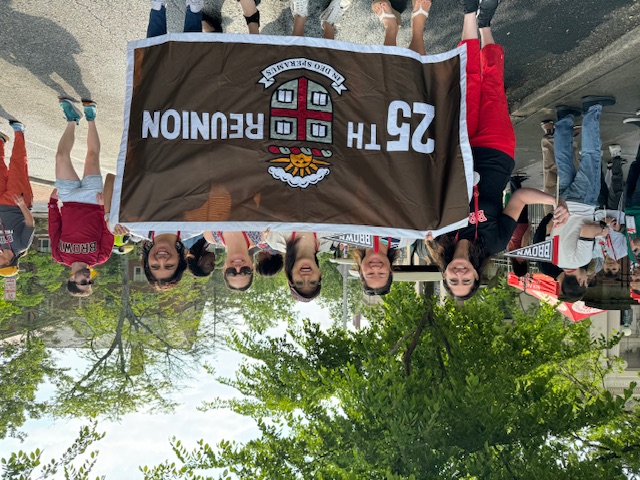Nisha and a group of classmates holding a 25th Reunion banner.