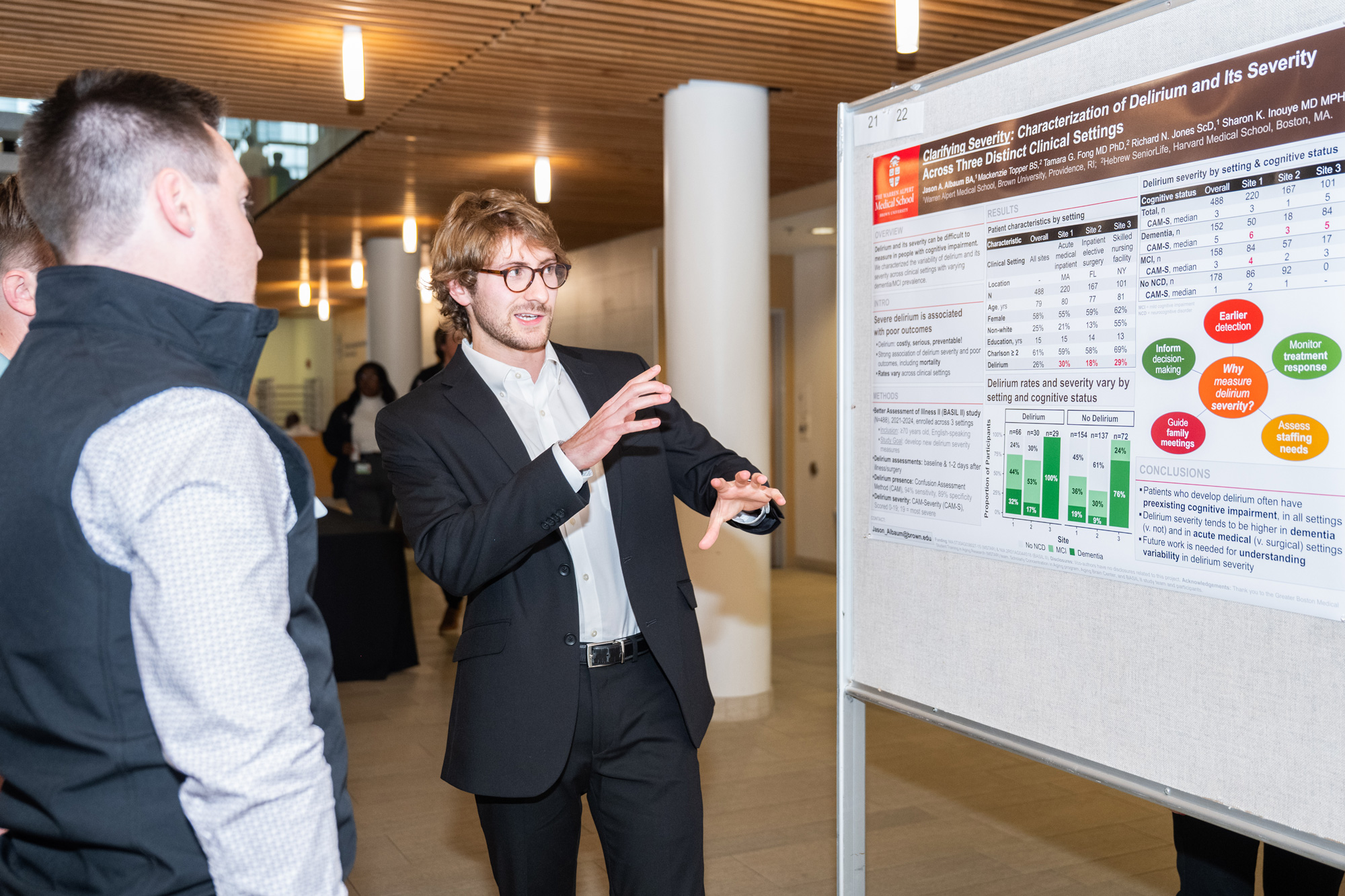 Jason Albaum stands in front of his research presentation board at a symposium.