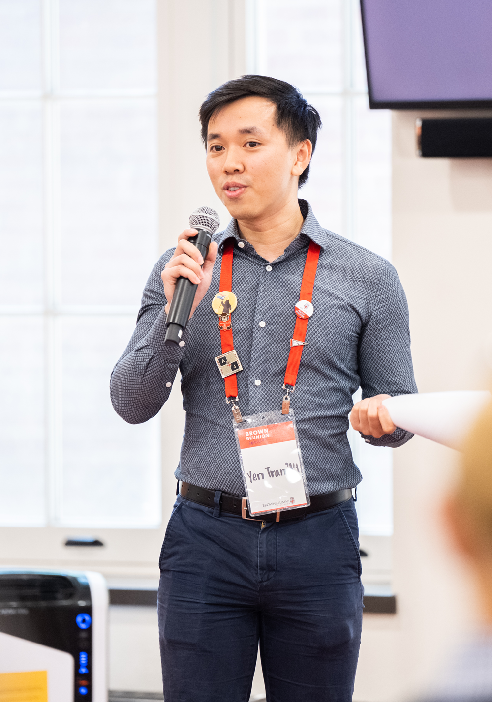 Yen speaks into a handheld microphone while standing.