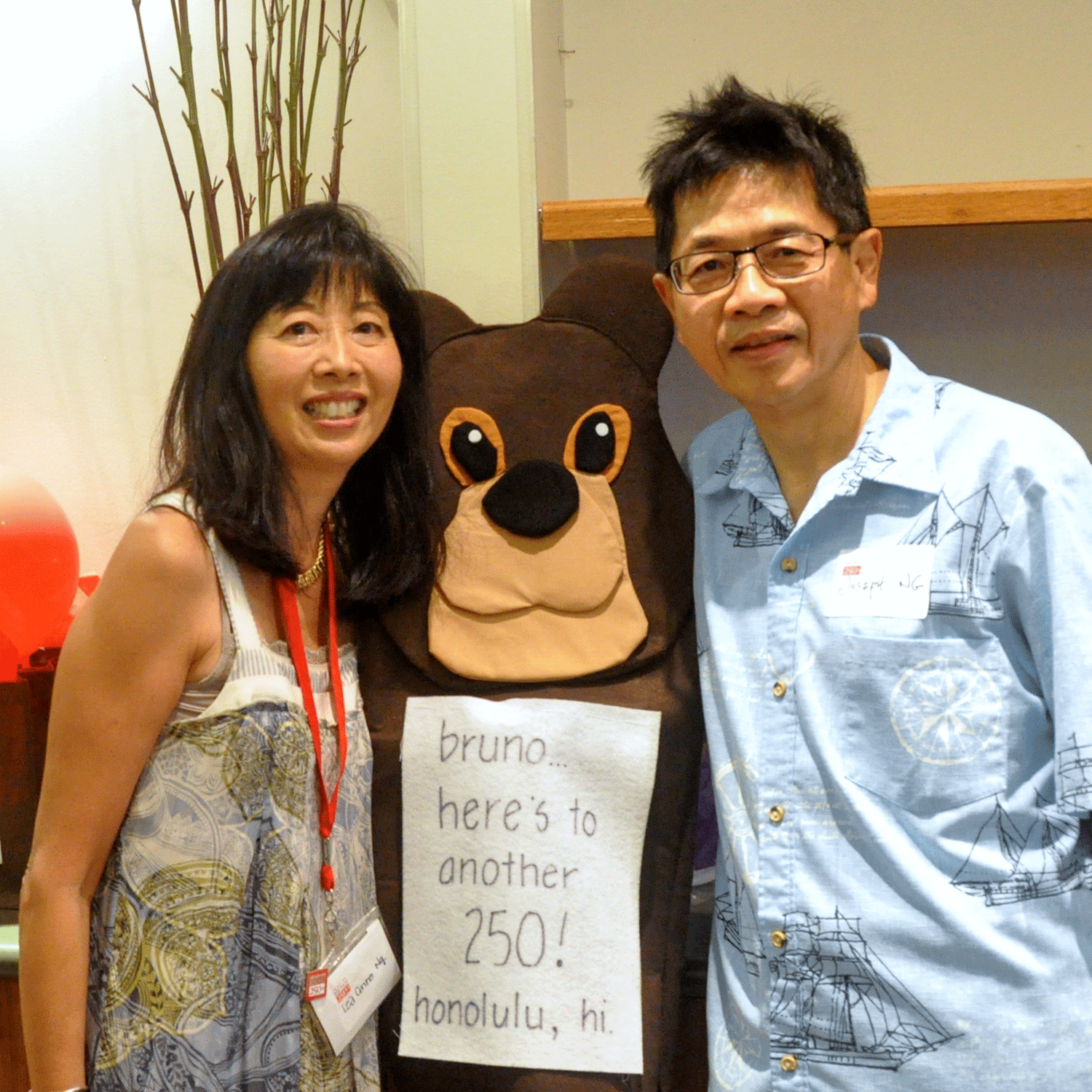 Lee Anne Ng '82 and her husband Joseph Ng pose with a display of the Bruno the Bear mascot.
