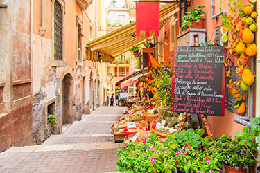 narrow street with restaurant displaying menu on chalkboard sign