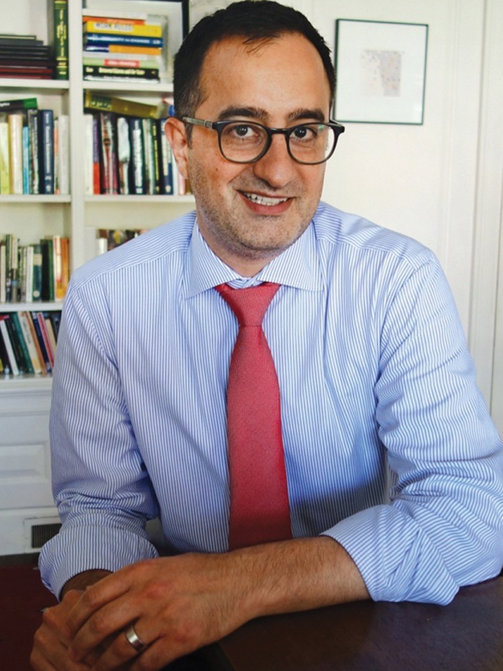 Dean of the College Rashid Zia '01 sitting at a desk in front of a bookcase