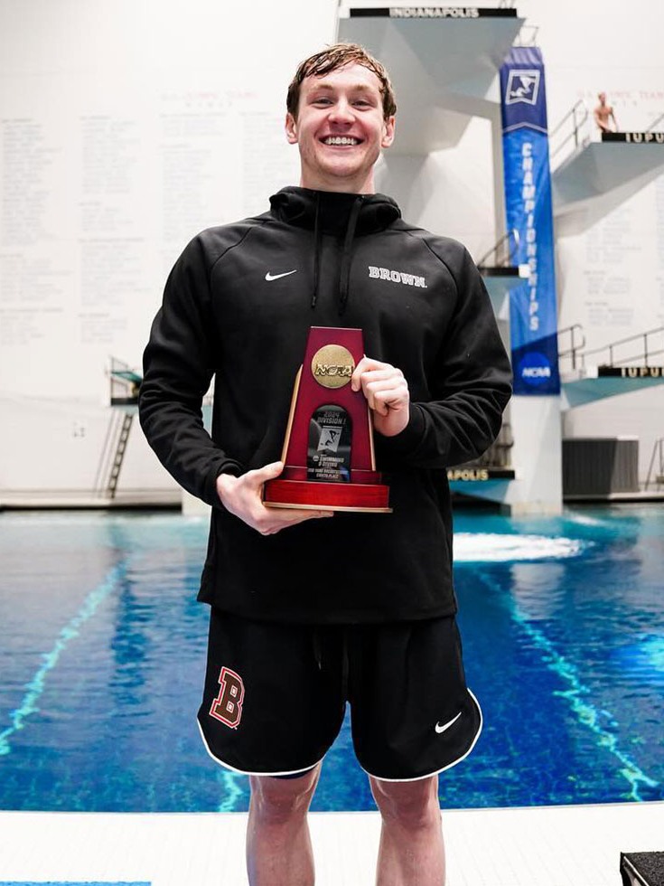 Jack Kelly smiling with award in front of swimming pool