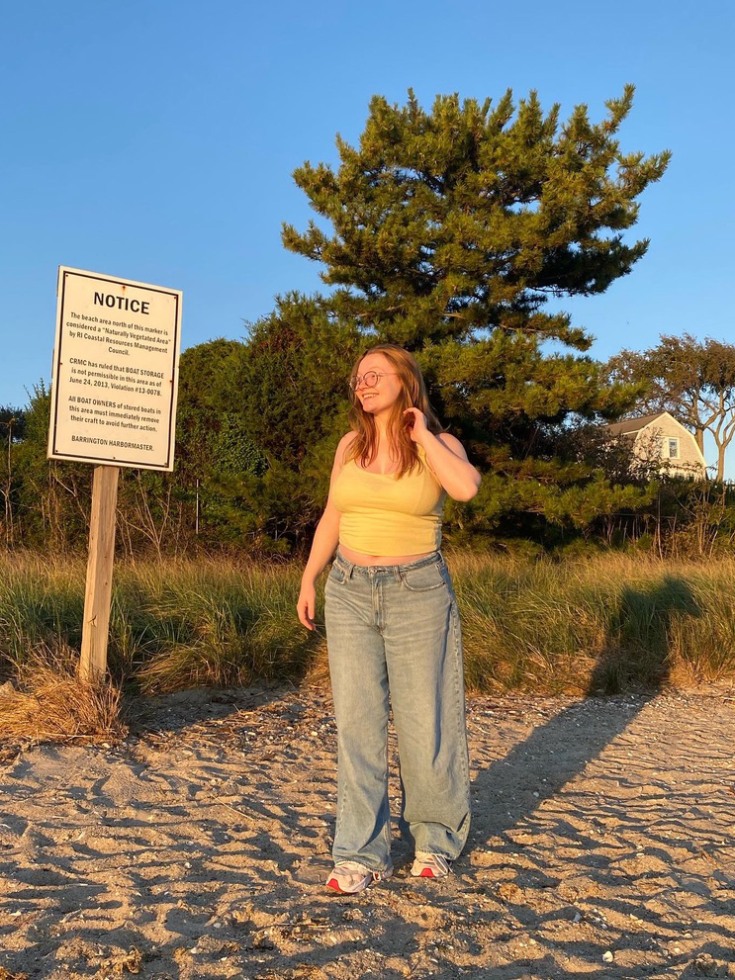 Hannan Fernandez poses near a sign along the beach.