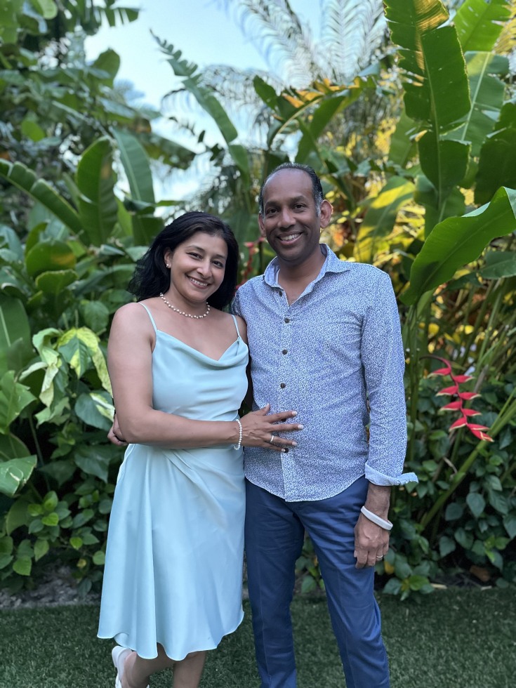 Arpana and Amish Shah posing in front of foliage outside.