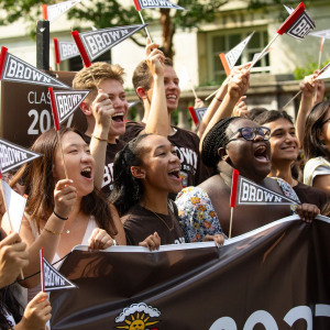 Students cheering at Convocation while waving Brown pennants