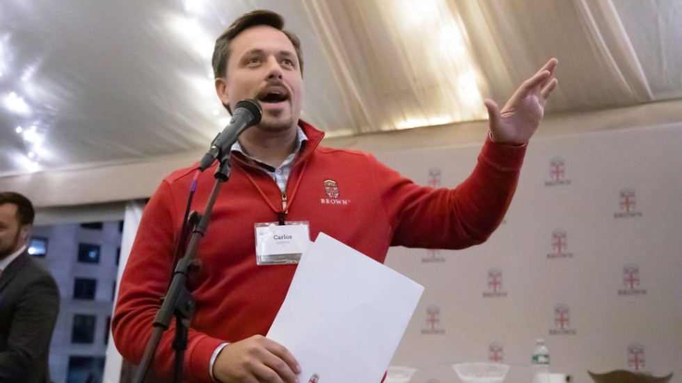 Brown Alumni Association President Carlos Lejnieks ’00 speaking at a microphone