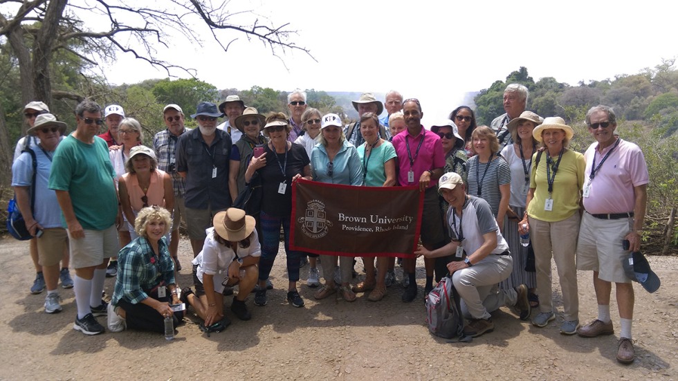 Alumni posing with Brown University banner at Victoria Falls