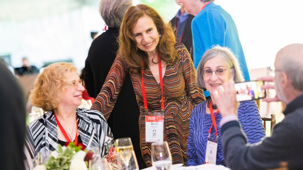 Alumni smiling, talking, and taking photos at a table during a class reception