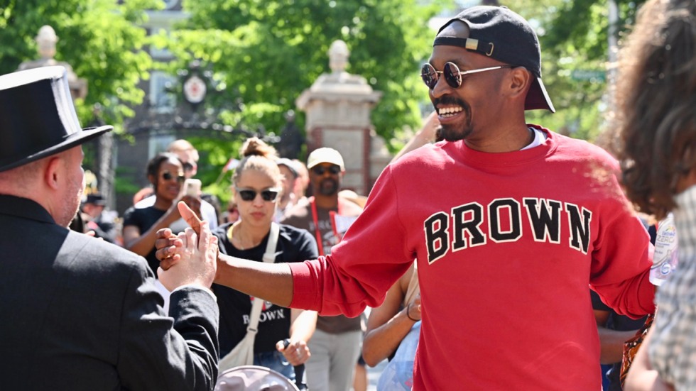 An alum wearing a Brown sweatshirt gives high fives during Procession