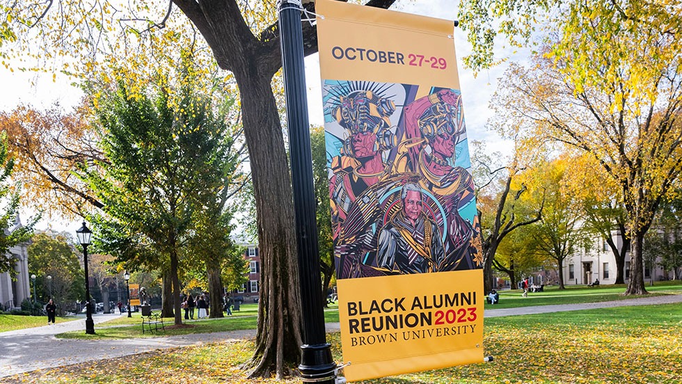 Black Alumni Reunion banner hanging from lamp post on campus green.