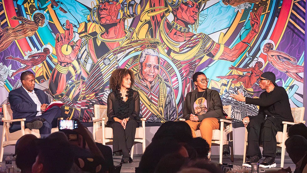 Panelists sit in front of colorful backdrop discussing the power of art in the Black narrative.