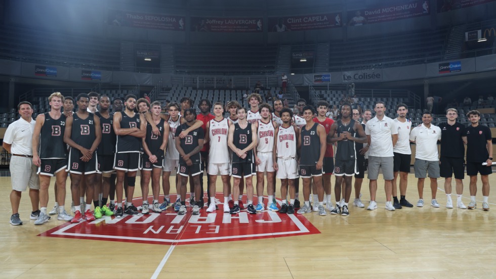 Brown men's basketball team poses with a French team after a match on the court.
