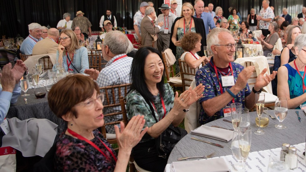 alums seated at a dinner table applauding