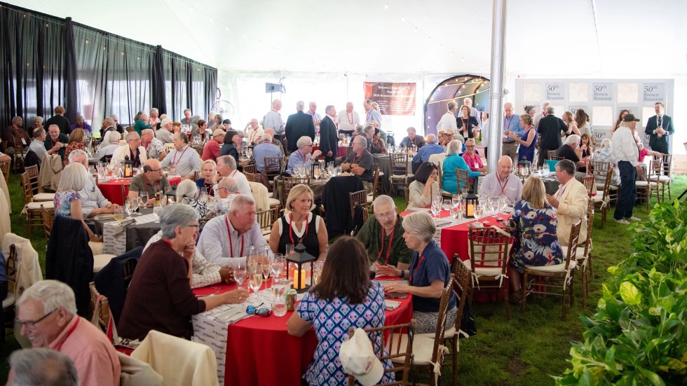 alums seated at tables under reunion tent