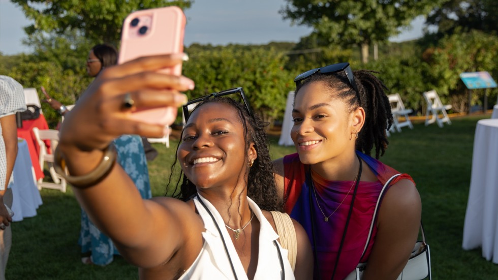 Two alumni pose for a selfie at the celebration.