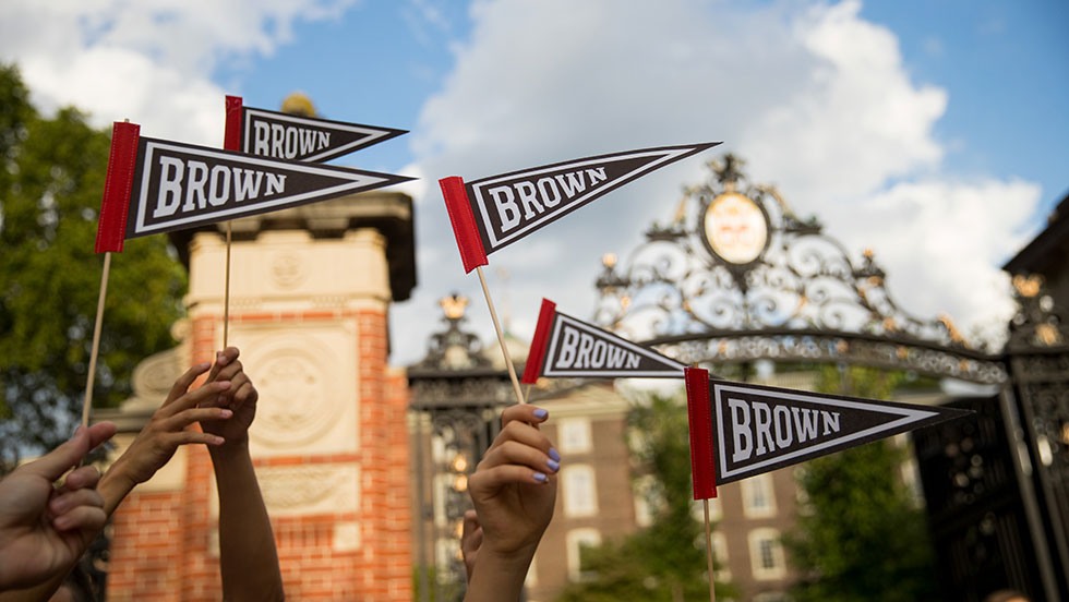Brown pennants being held up in front of Van Wickle Gates