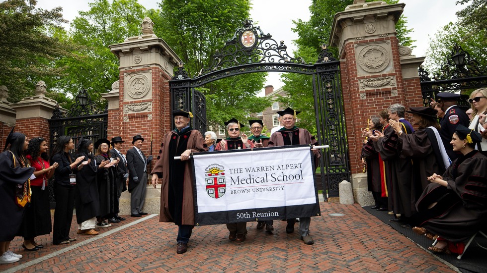 MD Class of 1975 alumni carry banner in front of Van Wickle Gates