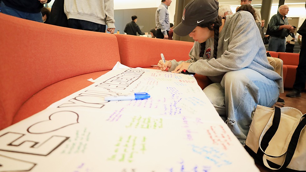A student signs the giant card for Hazeltine