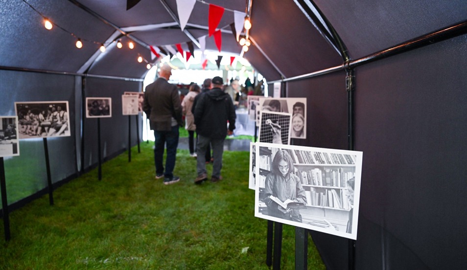 Members of the Class of 1975 walk through the tunnel to their class reception, adorned with archival photos from their time at Brown.