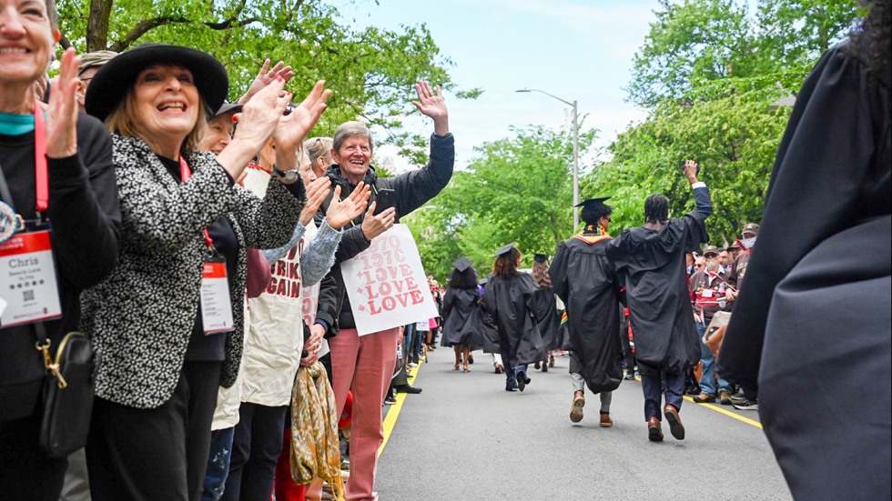 Alums from past classes lined up on the road to cheer on the new Brown graduates.