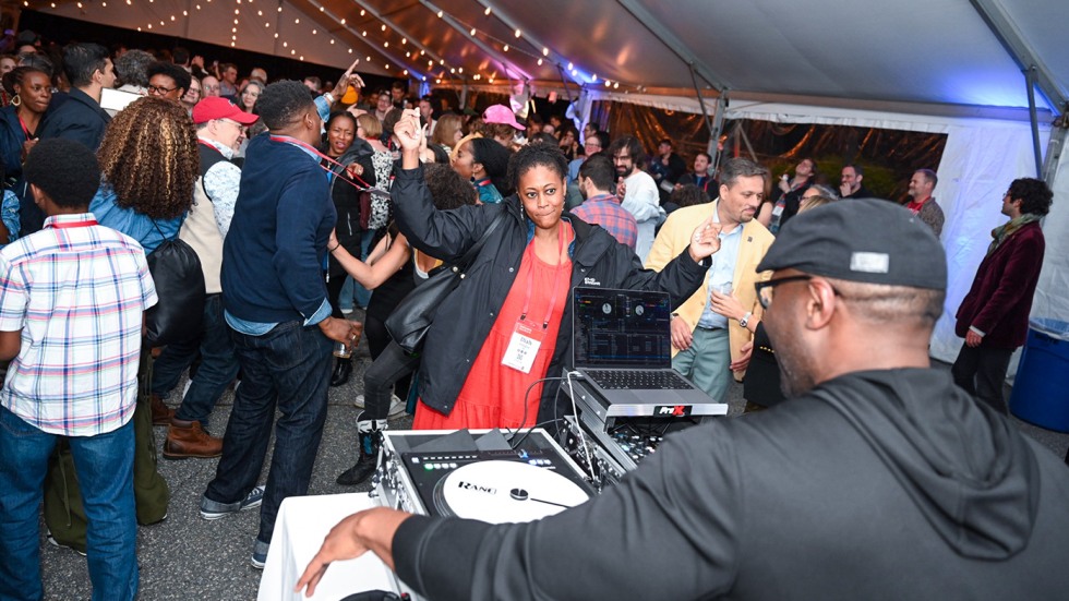Alums dancing at Unity Funk Nite under a tent with the DJ in the foreground.