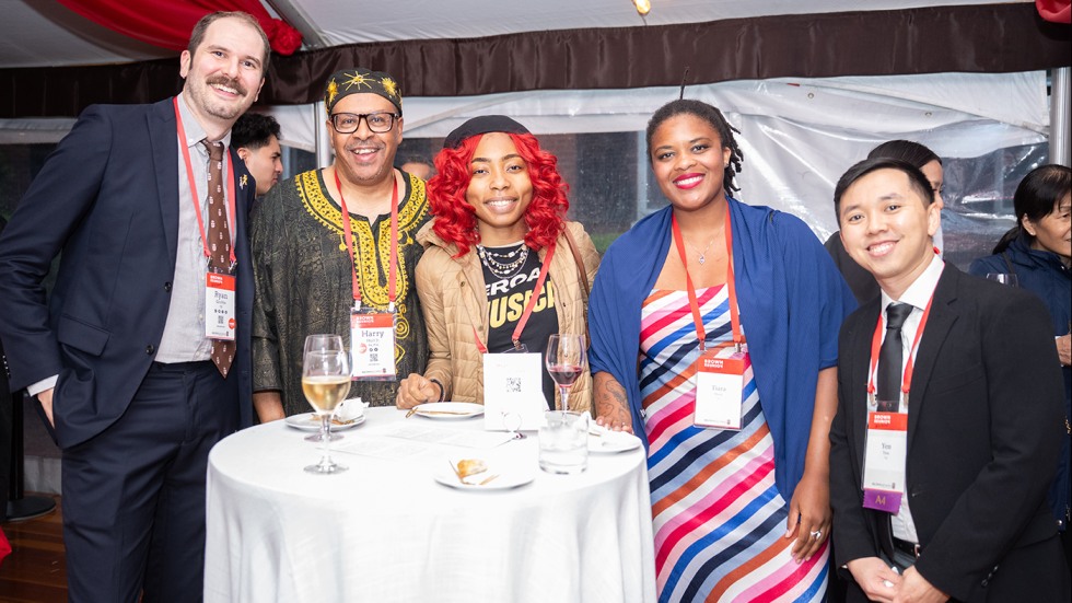 Five alums pose for a photo under the tent at Unity Celebration.