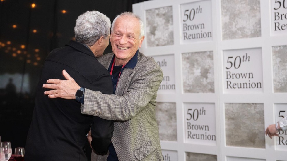 alums hugging in front of 50th reunion photos