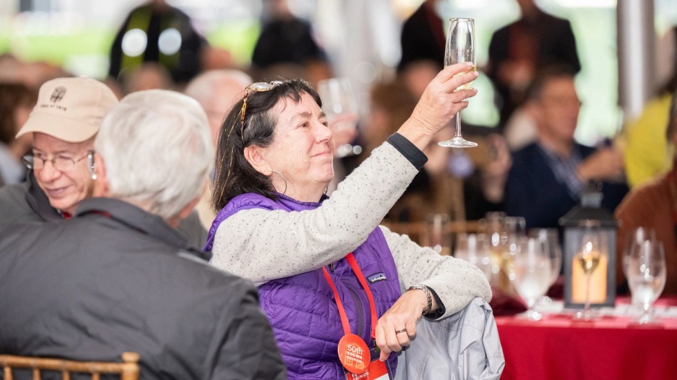 alum holding up a glass for a toast