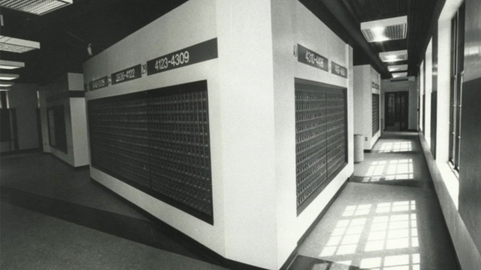 Interior of a hallway with mailboxes on either side, featuring numbers and signs indicating 'Student Mail.'
