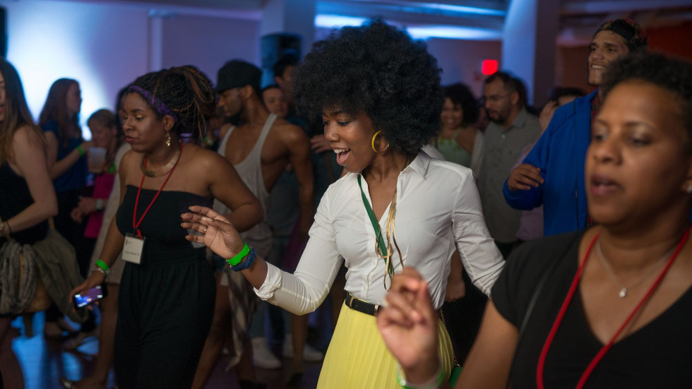 A group of people dancing in a dimly lit indoor space. 