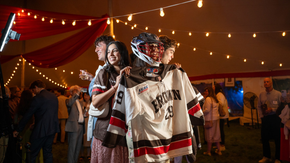 Student-athletes in a group holding up a jersey
