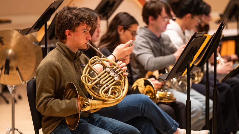 A group of musicians playing brass instruments during rehearsals.