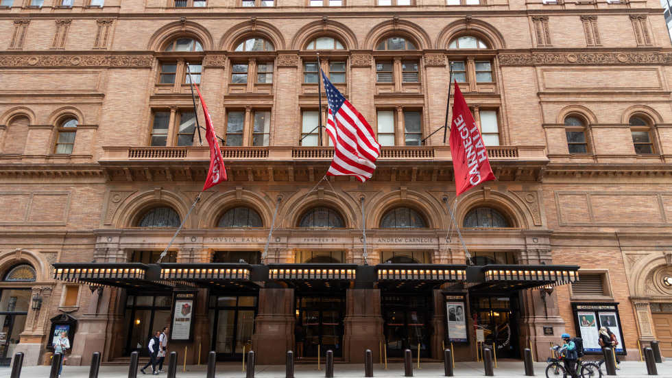 Exterior view of Carnegie Hall with flags displayed above the entrance. 