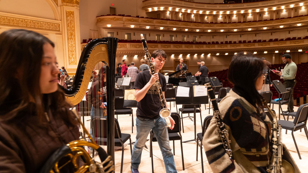 Musicians holding instruments during rehearsals, such as a harp and clarinet. 